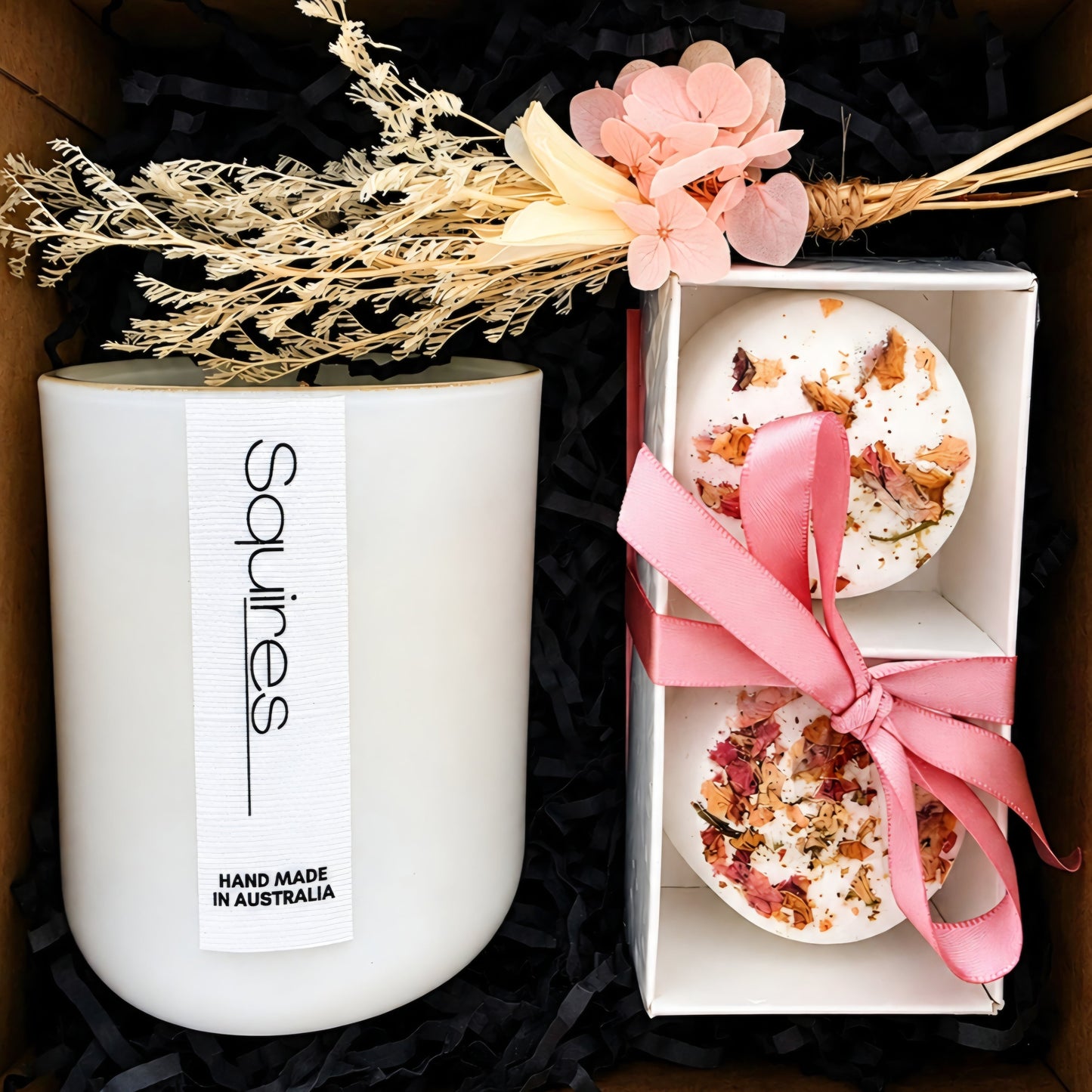 A gift set containing a Squires soy candle HAND MADE IN AUSTRALIA, relaxing shower steamers with a pink ribbon dried flowers on top.
