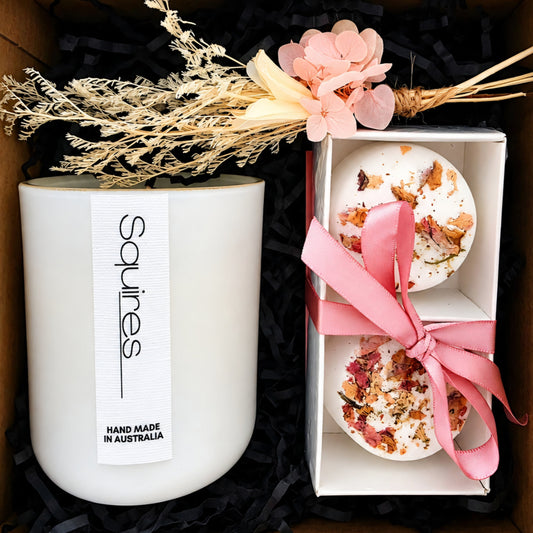 A gift set containing a Squires soy candle HAND MADE IN AUSTRALIA, relaxing shower steamers with a pink ribbon dried flowers on top.